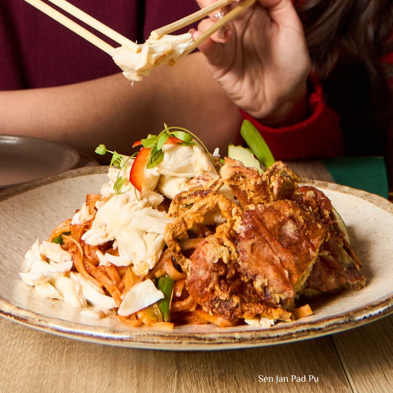 A person uses chopsticks to pick up crab meat from a plate of Sen Jan Pad Pu at Khaosan.